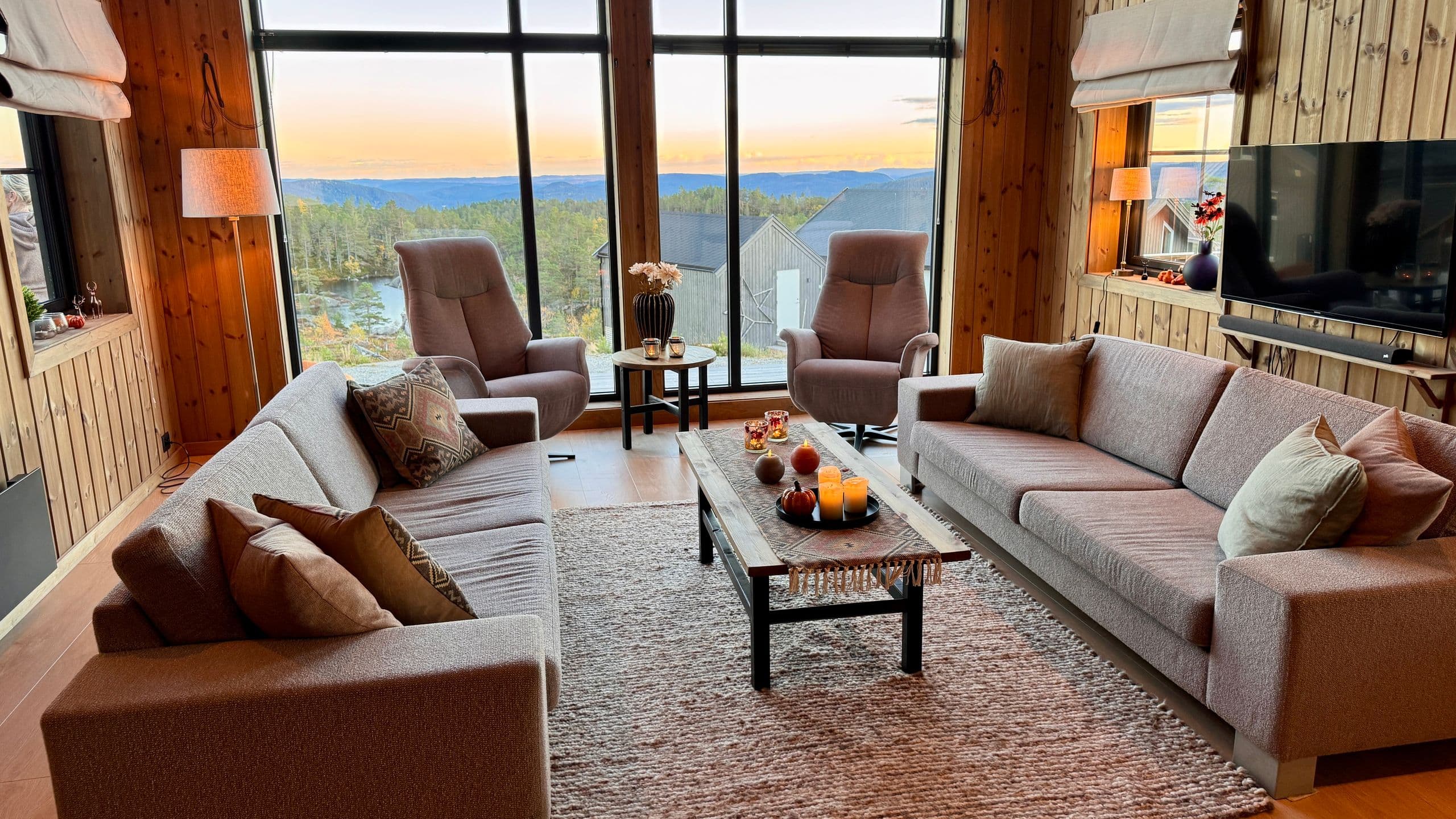 Wohnzimmer mit Sofas und großen Fenstern mit Blick in den Sonnenuntergang